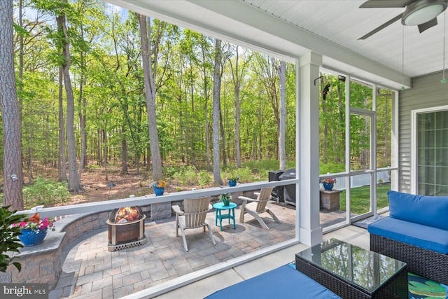 sunroom featuring an outdoor living space with a fire pit, a wealth of natural light, and a ceiling fan