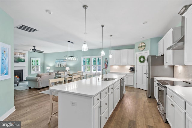 kitchen with a sink, a breakfast bar area, visible vents, ceiling fan, and appliances with stainless steel finishes