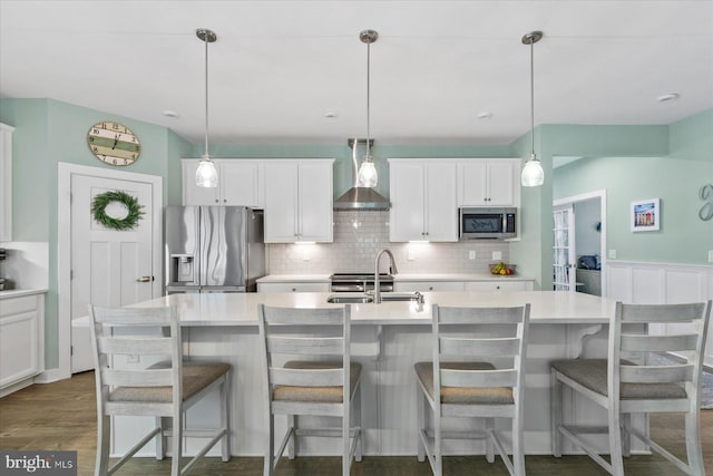 kitchen with stainless steel appliances, decorative backsplash, wall chimney range hood, light countertops, and white cabinets