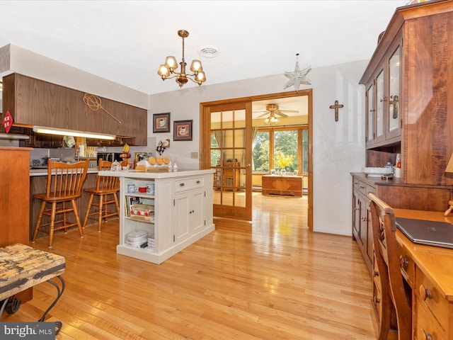 11615 Taneytown Pike, Emmitsburg, MD 21727 - kitchen featuring ceiling fan with notable chandelier, light wood-type flooring, visible vents, pendant lighting, and glass insert cabinets