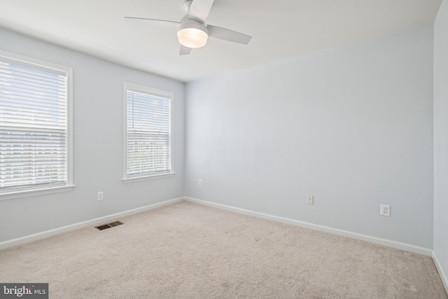 spare room with visible vents, a wealth of natural light, and carpet