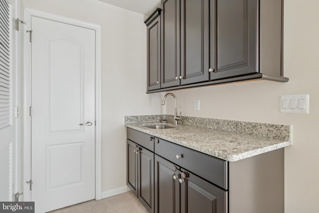 kitchen featuring light carpet, a sink, light countertops, baseboards, and gray cabinetry