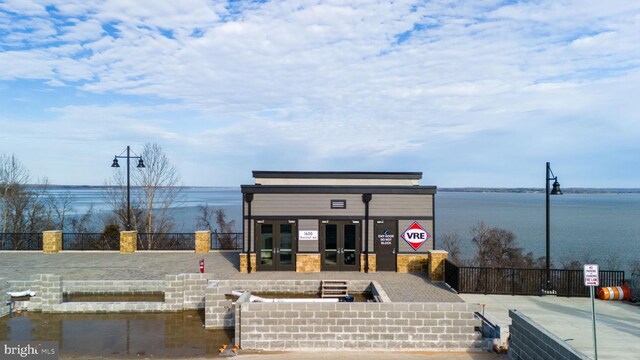 view of front of property with a water view, fence, and french doors
