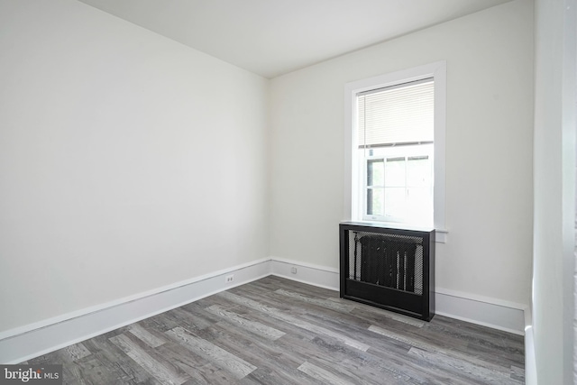 unfurnished room featuring baseboards, wood finished floors, and a fireplace