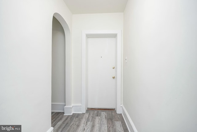 interior space with arched walkways, baseboards, and wood finished floors