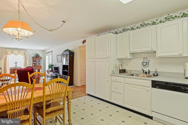 kitchen featuring white dishwasher, a sink, light countertops, an inviting chandelier, and light floors
