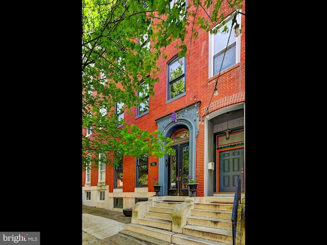 view of exterior entry featuring brick siding and french doors