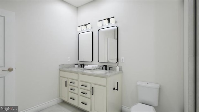 bathroom with a sink, baseboards, toilet, and double vanity