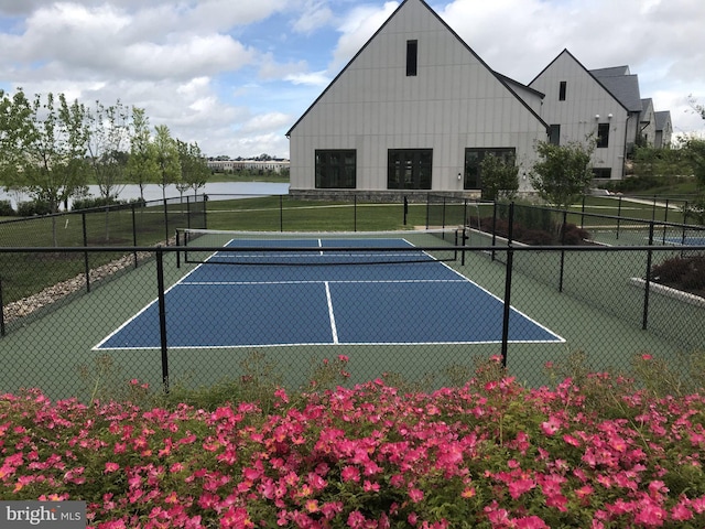 view of sport court with a water view and fence
