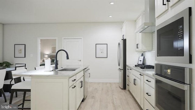 kitchen with a breakfast bar, a sink, light countertops, stainless steel appliances, and white cabinetry