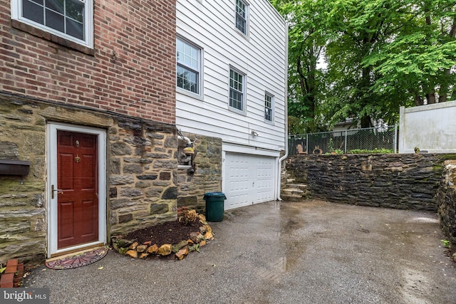 2948 Normandy Rd, Ardmore, PA 19003 - view of side of property featuring stone siding, fence, a garage, and asphalt driveway