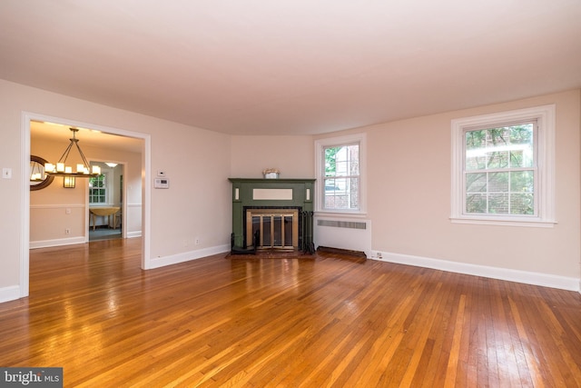 2948 Normandy Rd, Ardmore, PA 19003 - unfurnished living room with radiator, light wood-style flooring, a chandelier, a fireplace with flush hearth, and baseboards