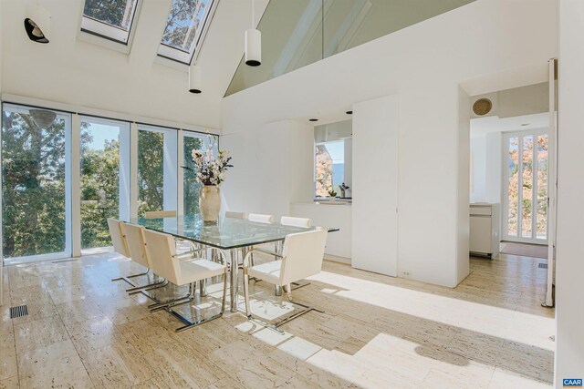 dining area featuring a skylight, visible vents, and a towering ceiling