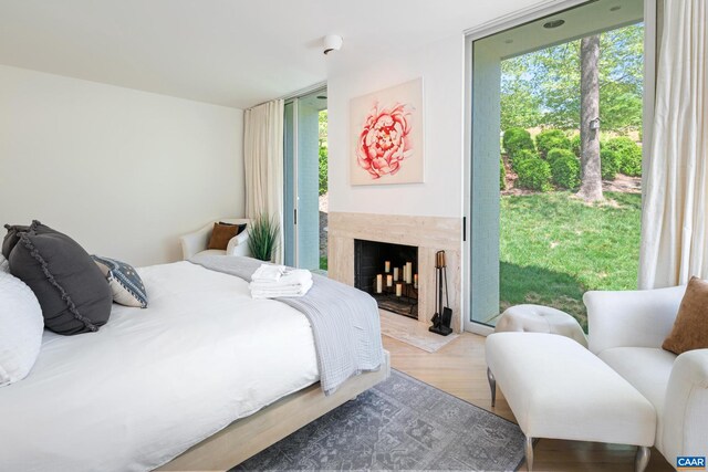 bedroom with a high end fireplace, wood finished floors, and access to exterior