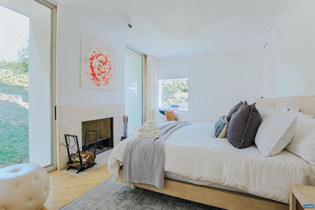 bedroom with a glass covered fireplace and wood finished floors