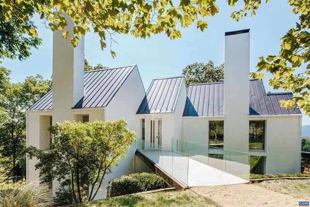 rear view of property with a standing seam roof, metal roof, and a chimney