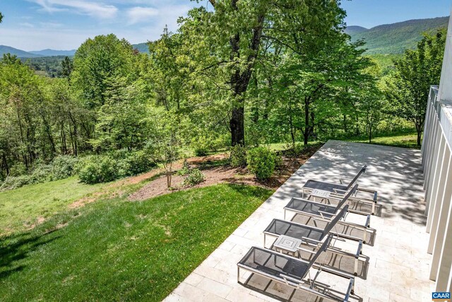 exterior space with a patio, a view of trees, and a mountain view