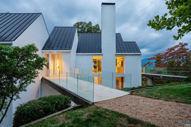back of property featuring metal roof, a chimney, and a standing seam roof