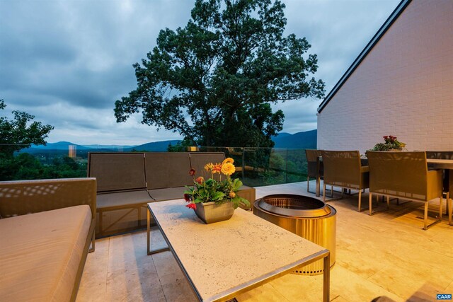 view of patio featuring an outdoor fire pit, a mountain view, and a balcony