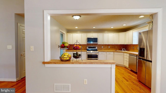 609 Quartzite Cir, Winchester, VA 22601 - kitchen featuring visible vents, a peninsula, light wood-style floors, stainless steel appliances, and white cabinetry