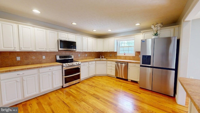 609 Quartzite Cir, Winchester, VA 22601 - kitchen with white cabinets, a sink, light wood finished floors, light countertops, and stainless steel appliances