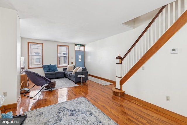 living area with stairway, baseboards, and wood finished floors