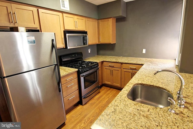 kitchen featuring light stone countertops, light wood-style flooring, visible vents, a sink, and stainless steel appliances
