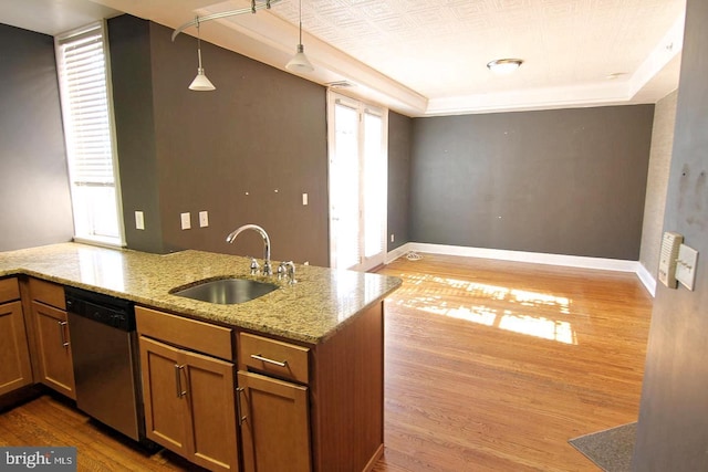 kitchen with stainless steel dishwasher, light stone counters, a sink, brown cabinets, and light wood-type flooring