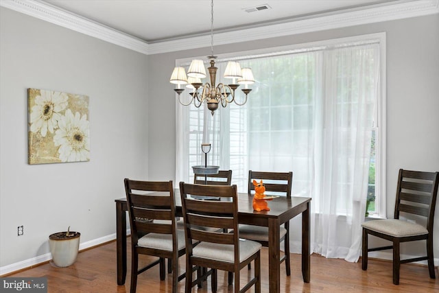 dining room with visible vents, ornamental molding, an inviting chandelier, and wood finished floors