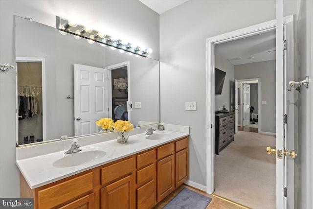bathroom featuring double vanity, a sink, baseboards, and a spacious closet