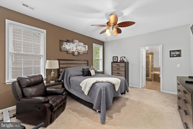 bedroom with visible vents, light carpet, baseboards, ceiling fan, and ensuite bath