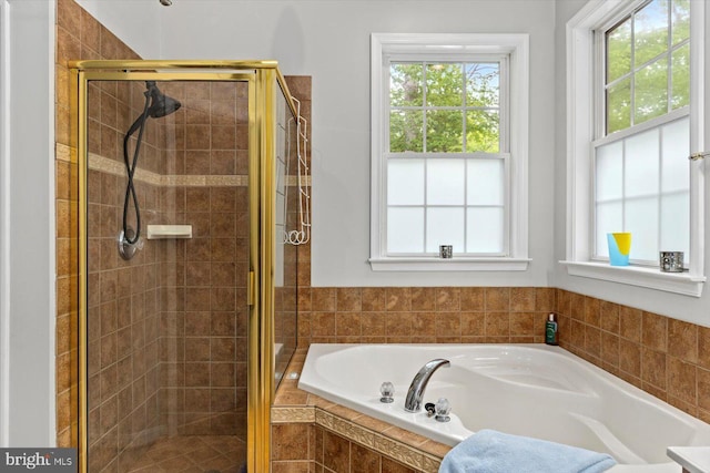 full bath with a healthy amount of sunlight, a stall shower, and a bath