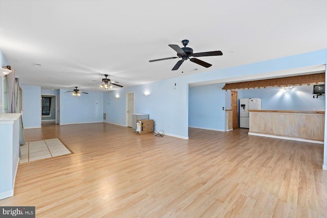 unfurnished living room featuring baseboards, ceiling fan, and wood finished floors