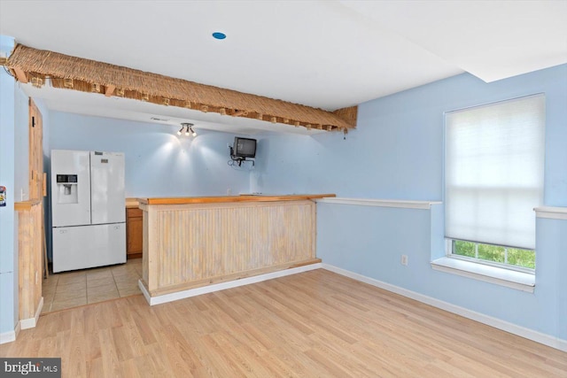 kitchen with baseboards, light wood finished floors, and white fridge with ice dispenser