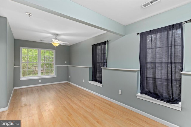 spare room with baseboards, ceiling fan, wood finished floors, and visible vents