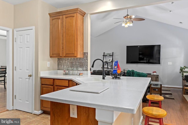 kitchen featuring ceiling fan, a sink, light countertops, a peninsula, and decorative backsplash