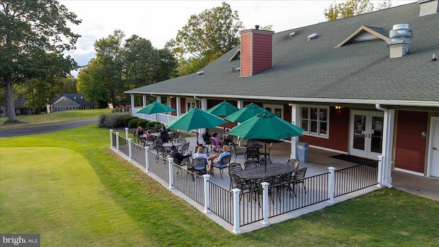 rear view of house featuring fence, a patio, french doors, a chimney, and a lawn