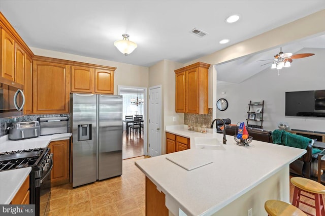 kitchen with visible vents, a peninsula, a breakfast bar area, a sink, and stainless steel appliances