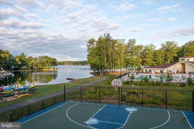view of sport court with a yard, a water view, community basketball court, and fence
