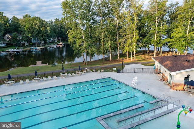 pool featuring a water view, a patio area, and fence