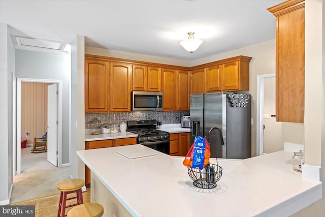 kitchen with tasteful backsplash, light countertops, a peninsula, a breakfast bar, and stainless steel appliances