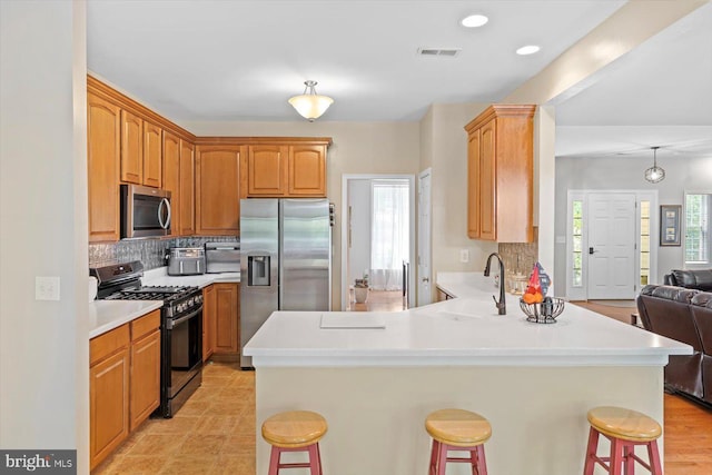 kitchen with a kitchen breakfast bar, stainless steel appliances, open floor plan, a peninsula, and visible vents