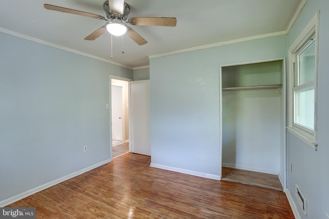 unfurnished bedroom with crown molding, a closet, wood finished floors, and visible vents