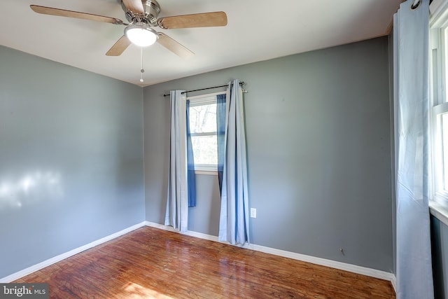 spare room with baseboards, ceiling fan, and wood finished floors