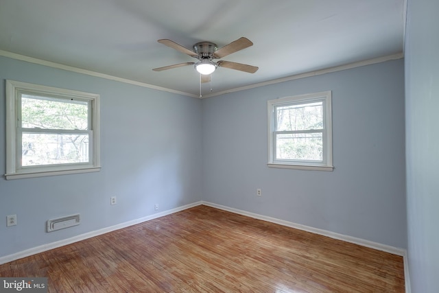 empty room featuring crown molding, baseboards, ceiling fan, and wood finished floors