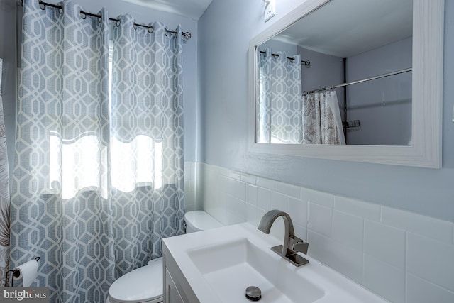 full bath featuring vanity, a shower with shower curtain, toilet, and tile walls