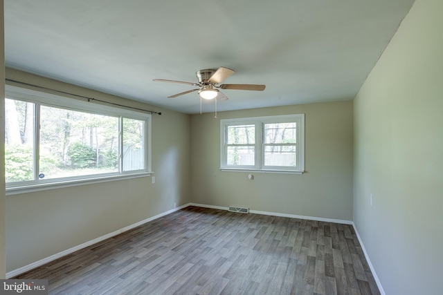 spare room featuring baseboards, a ceiling fan, wood finished floors, and visible vents