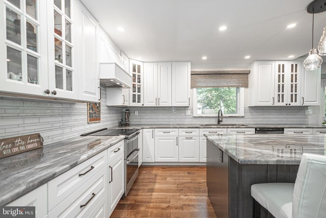 kitchen with appliances with stainless steel finishes, wood finished floors, light stone countertops, and tasteful backsplash