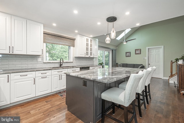 kitchen with backsplash, light stone countertops, a sink, and hardwood / wood-style flooring