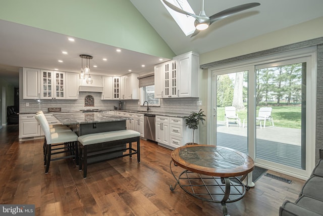kitchen with appliances with stainless steel finishes, a sink, a center island, white cabinetry, and decorative backsplash